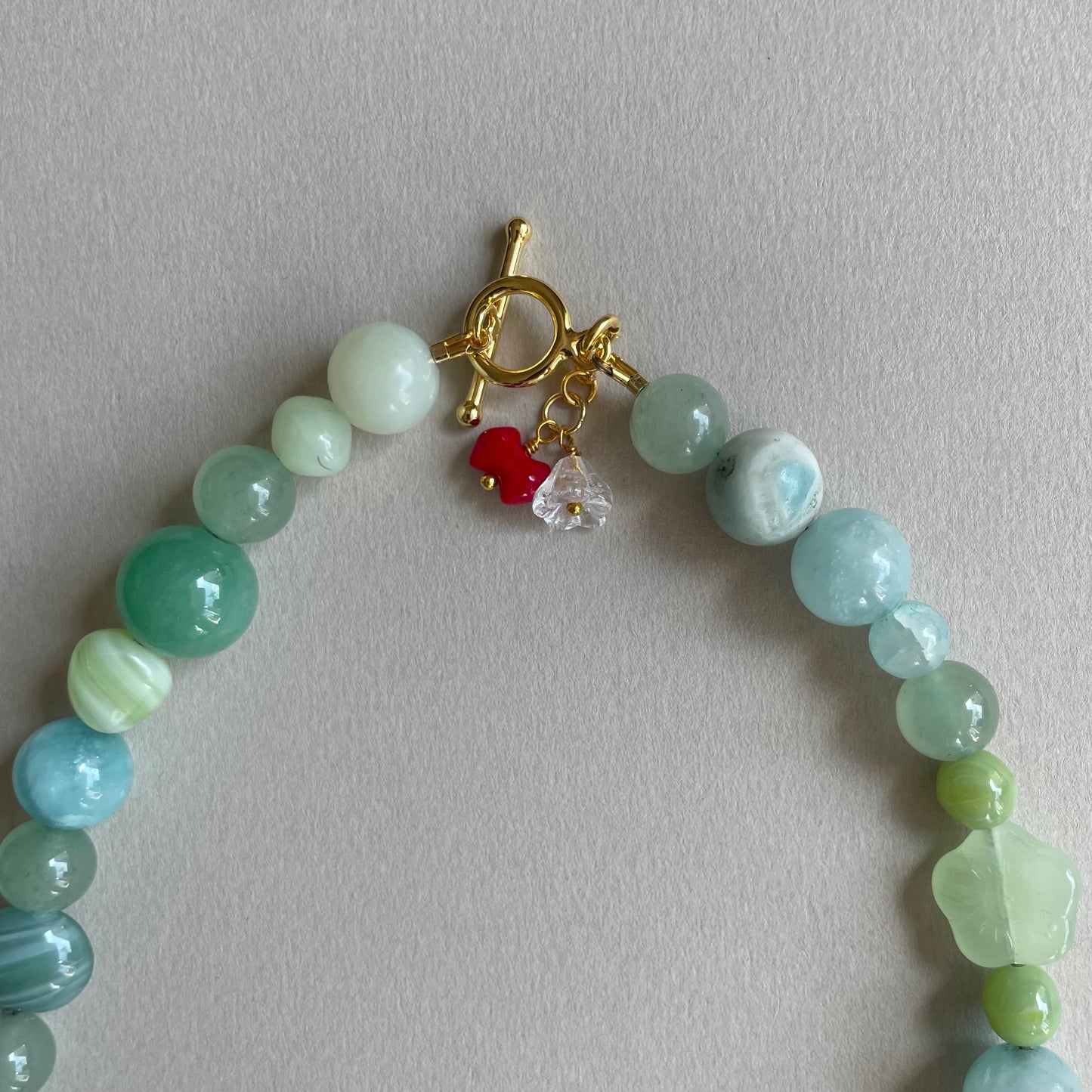 Håndlavet halskæde med et smukt mix af glas & vintage perler i grønne nuancer og med et lille fint charm.