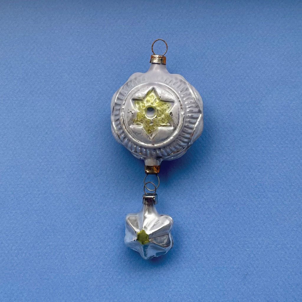 Jule ornament med måne og stjerne på hver sin side og en dinglende stjerne for neden